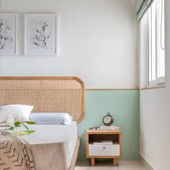 The primary room in 'Living life in colours' features a mellow, subtle palette. The custom bed with a cane headboard is complemented by sage green half-wall paneling.