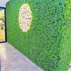 Your brand can be part of the design. For this cafe, we embedded a backlit logo directly into the artificial green wall, creating a vibrant and welcoming feature wall that strengthens the brand's identity.