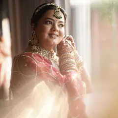 The final touches. This candid shot captures the soft, glowing makeup we created, highlighting her features beautifully in the natural light. The look is completed with elegant green-accented jewelry.