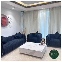 We designed this living room to feel both luxurious and welcoming. The deep navy blue, channel-tufted sofa and matching armchairs are paired with a solid marble block coffee table, creating a bold, contemporary look grounded in classic comfort.