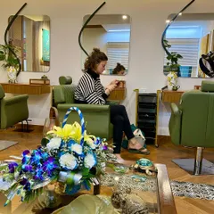 A wide view of our salon area, showing the clean, open layout with comfortable seating and elegant decor, ready to welcome our clients.
