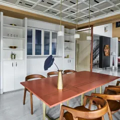 This dining room features a custom copper-topped table with brass legs, paired with classic wooden chairs. The coffered ceiling and built-in white cabinetry add a touch of timeless elegance.