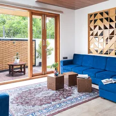 The living room of the Cube House opens onto a patio through large sliding glass doors. This seamless transition extends the living area outwards and fills the interior with natural light.