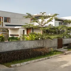 Viewed from the street, The Quarry House presents a layered facade of concrete, glass, and greenery. The boundary wall, constructed from the same concrete, integrates seamlessly with the main structure and the thoughtfully designed landscape.