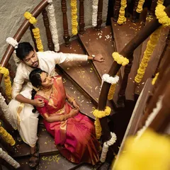 An intimate moment captured from above on a spiral staircase decorated with flowers. This unique angle provides a beautiful, storytelling perspective for an indoor pre-wedding shoot.