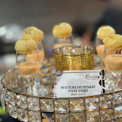 A creative fusion appetizer: Pani Puri shells filled with a waterchestnut and Thai curry mixture, served in elegant glasses.