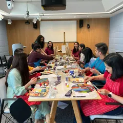 A lively table of Google employees fully engaged in the painting process. These workshops are designed to be fun and accessible, helping everyone unwind and express their creativity.