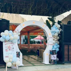 A welcoming entrance for Kiyansh's first birthday carnival, with a custom sign and pastel blue and white balloon decorations.