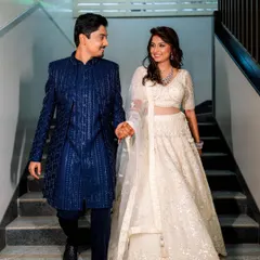 This client couple is the perfect example of subtle coordination. Her white sequined lehenga and his deep blue bandhgala create a classic and elegant pairing for their reception.