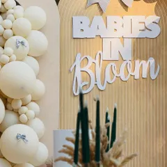 The custom 'Babies in Bloom' signage adds a personalized and stylish touch to the neutral-toned, fluted backdrop.
