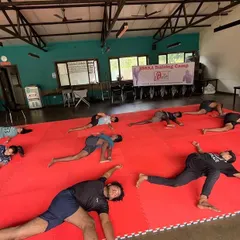 Flexibility is crucial for preventing injuries and executing advanced techniques. This image shows our athletes in a deep stretching pose, working on their hip and leg flexibility as part of our integrated yoga for fighters program.