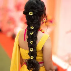 A beautiful braided hairstyle for a Haldi ceremony, adorned with delicate yellow flowers.