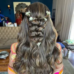 A beautiful and intricate half-up style for a Mehendi function. I created a waterfall braid down the center and adorned it with delicate white flowers, while the rest of the hair flows in soft waves.