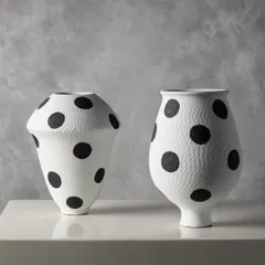 Here are two variations of our polka dot ceramic vases. Their contrasting shapes, one wide and one tall, create a dynamic pairing that adds a touch of whimsy and graphic appeal to a console or shelf.