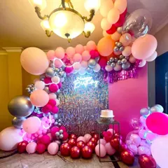 A glamorous birthday setup for a wife, featuring a pink and silver shimmer wall as the centerpiece. The wall is framed by a dramatic balloon arch in coordinating colors, creating a luxurious photo corner at home.