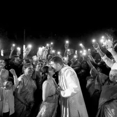 A kiss under the light of a hundred phones. This candid shot captures the couple's private moment in a public celebration, a modern take on a classic wedding memory.