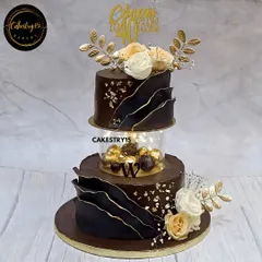 Celebrating a 40th birthday calls for something truly special. This two-tier chocolate cake features a modern, luxurious design with bold chocolate sails, an illuminated spacer, and elegant floral toppers, creating a sophisticated centerpiece for a milestone event.