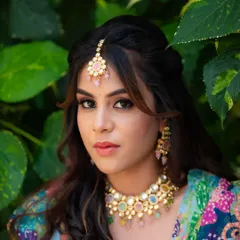 A close-up portrait focusing on the bride's makeup and jewelry. The soft pink and green tones of her accessories are perfect for a daytime Mehendi event.