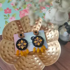 These black fabric earrings are a great example of my handmade work. They feature yellow floral embroidery and dangling yellow beads, making them a cheerful and stylish accessory.