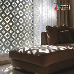 Inside, the 'jaali' screen filters the harsh sunlight, casting intricate geometric shadows across the living room and furniture, creating a dynamic and ever-changing ambiance.