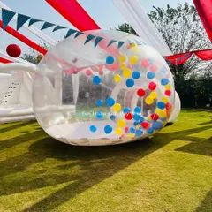 The Bubble House filled with primary-colored balloons, set up under a tent for a circus-themed party. It adds a modern twist to a classic theme.