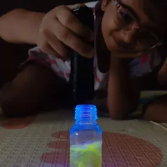 A young scientist completely absorbed in her experiment. Using a UV light, she discovers the magical glowing properties of her creation, a perfect example of screen-free, hands-on learning.