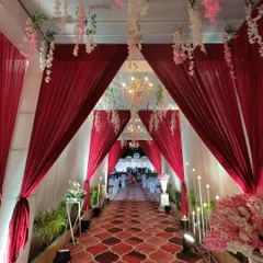 A classic and elegant entrance is always a beautiful choice. Here, I used rich red and white drapes to create a long, inviting walkway, illuminated by warm candlelight and delicate hanging floral arrangements.