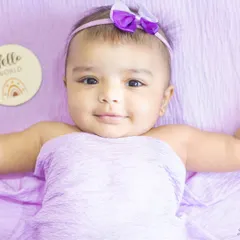 A calm and gentle portrait of a baby girl with a 'Hello World' milestone card. These sessions are perfect for tracking your baby's growth.