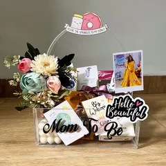 The cutest acrylic "Mom to be" basket hamper for the sweetest one. It's filled with goodies for the mommy-to-be, including a polaroid of her, chocolates, and a "You're the sprinkles to my donut" sign.