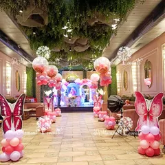 The entire venue is transformed into a butterfly garden with themed balloon pillars and hanging decor, creating an immersive experience from the moment guests walk in.