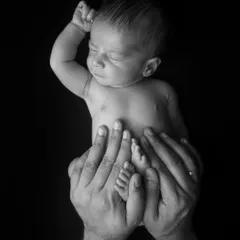 A newborn's tiny foot resting in their father's hand. This detailed black and white shot is a beautiful way to remember just how small they once were.