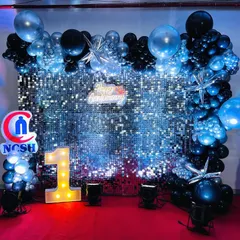 A sleek and modern backdrop with a silver shimmer wall. The black and metallic blue balloon frame, along with a light-up number '1', creates a stylish and eye-catching decoration for a first birthday.