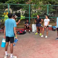 A typical moment on our court. A coach leads a group discussion, breaking down strategy and mindset. It's not just about hitting balls, it's about understanding the game.