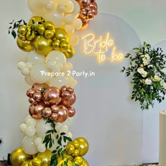 A closer look at our chic bridal shower decor, highlighting the "Bride to be" neon sign and the detailed balloon artistry. The combination of chrome gold, rose gold, and cream balloons with sprigs of greenery creates a refined and stylish look.