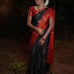 A full-length shot capturing a candid, happy moment during a Makar Sankrant photoshoot. The natural laughter and elegant drape of the black saree are the highlights of this image.