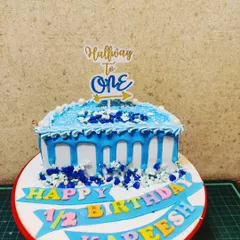 Another take on the half-birthday, this "Halfway to One" cake features a blue drip design and a celebratory banner for a baby boy.