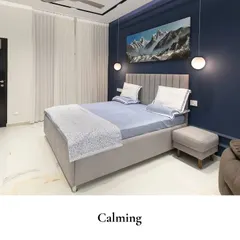 A calming bedroom that blends a deep navy accent wall with soft grey textures for a serene retreat. The artwork of snowy mountains adds to the cool, tranquil atmosphere, while globe pendant lights provide a soft, ambient glow.