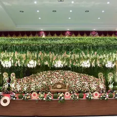A wide-angle view of a magnificent wedding stage, showing the scale of our floral work. We use a combination of dense flower arrangements and hanging greenery to create depth and a sense of luxury.