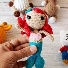 My crochet mermaid doll, with her bright red hair and blue tail, is ready for an underwater adventure. She's a popular character for imaginative play.