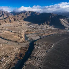 An aerial view of the high-altitude desert landscape surrounding Leh. The intricate patterns of the river valley and fields are stunning from above.