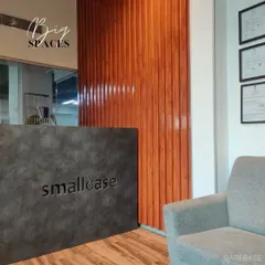 We create impactful reception areas. This project for Smallcase features a concrete-finish desk set against a backdrop of glossy, fluted wood wall paneling for a look that's both industrial and warm.