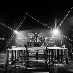 A view from the stage during soundcheck for 'The Wonderment Tour'. This black and white shot highlights the intricate lighting rig and stage structure before the audience arrives, showing the calm before the storm.