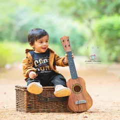Finding his rhythm. Musical props like this ukulele are a wonderful way to engage a child and capture their natural curiosity and playful expressions.