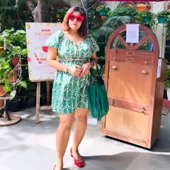 Posing in my green and red outfit in a sunny outdoor cafe setting.