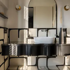Another view of the monochrome bathroom, where sunlight from the window creates a dramatic play of light and shadow on the graphic floor and wall tiles.