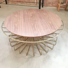 The Bloom coffee table combines a delicate, handcrafted metal wire base with a smooth wood top. The intricate gold-finished frame provides an airy, sculptural feel while offering sturdy support.