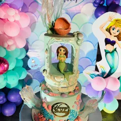 An elaborate two-tier mermaid cake with a unique 'underwater grotto' design on the top tier. This cake was the star of a mermaid-themed party, complete with a balloon backdrop.