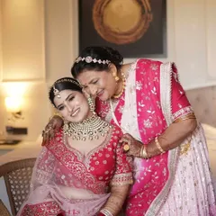 A vision in red. This bride shares a tender moment with her mother, her soft glam makeup and radiant smile capturing the joy of the day.