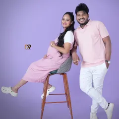 A fun and casual couple's portrait. The parents-to-be are coordinated in pink and white, creating a light, airy, and joyful photo that perfectly captures their personalities.