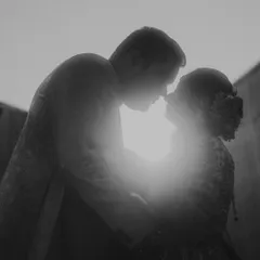 A powerful black and white silhouette of a couple about to kiss, backlit by the sun. This artistic engagement photo plays with highlights and shadows to create a timeless, dramatic, and emotional portrait.